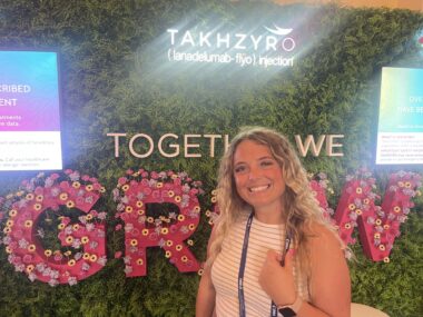 A woman poses in front of a green wall with the words "Together we grow" on it. 